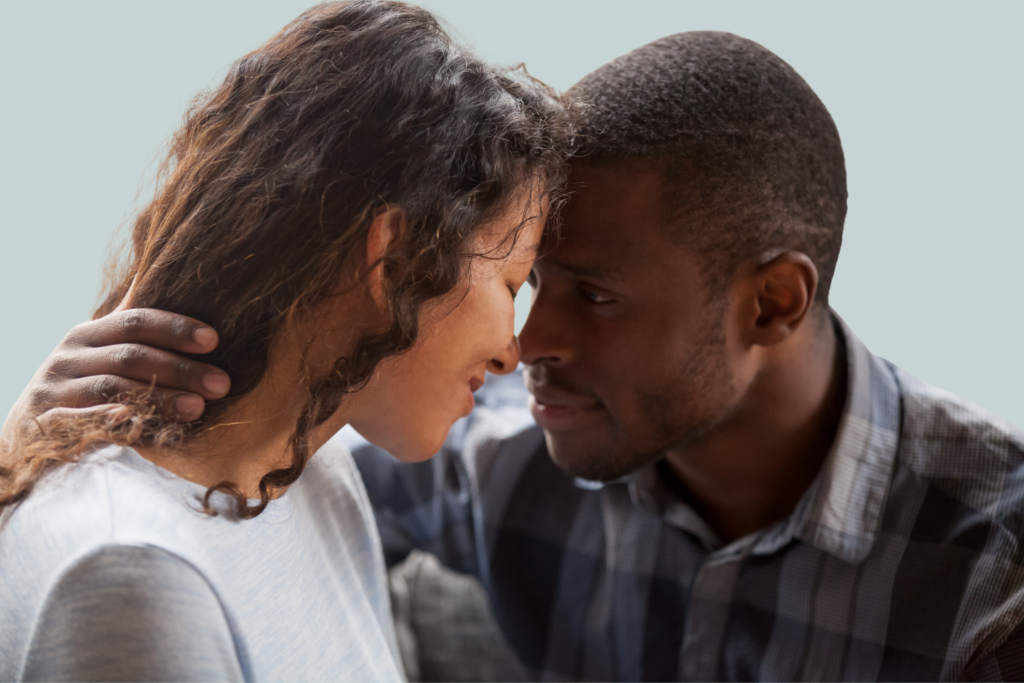A man and a woman touch foreheads together as he places a hand on the back of her neck