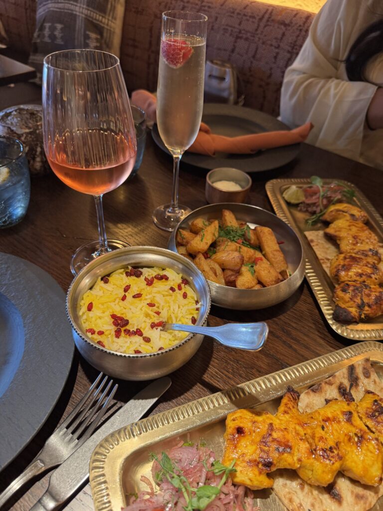 A table full of food including rice, chips and chicken, with two glasses of drink