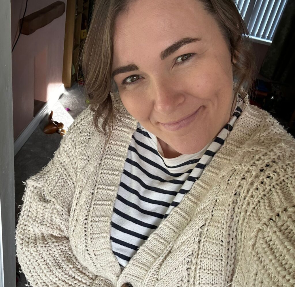 a woman in a cardigan and striped t-shirt smiles at the camera