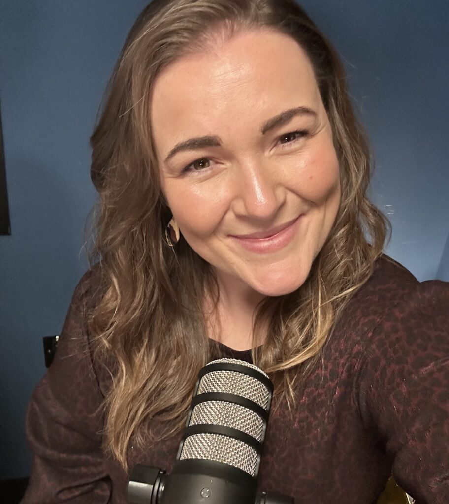 A brunette woman smiles in front of a microphone