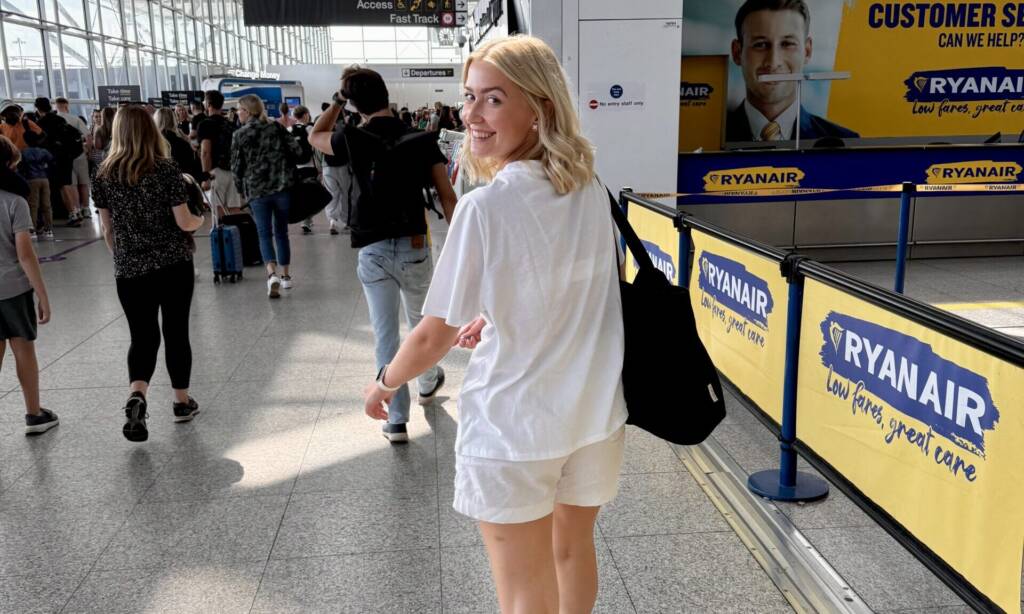 A blonde woman looks back and smiles as she walks through an