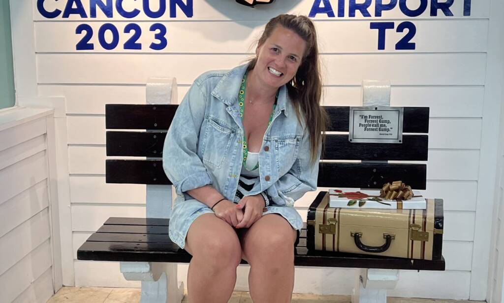 A woman in a blue jack on a bench at Cancun airport.